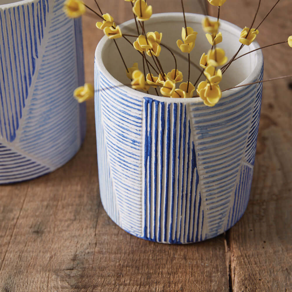 Blue and white geometric textured ceramic pot with yellow floral accents, perfect for home decor and plant display.