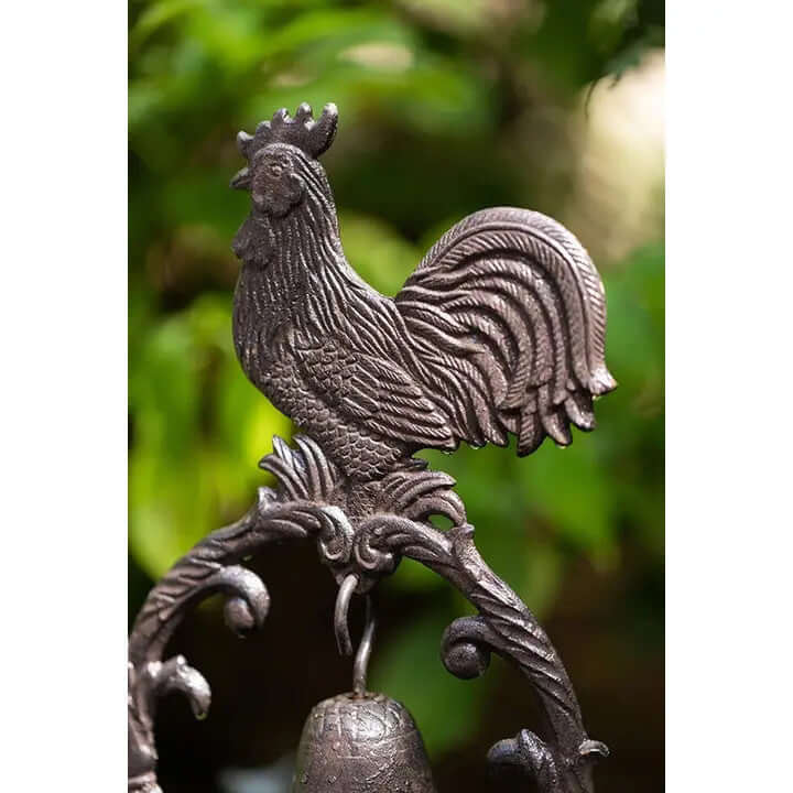 Close-up of a beautifully detailed cast iron rooster atop a rustic dinner bell, perfect for farmhouse decor.