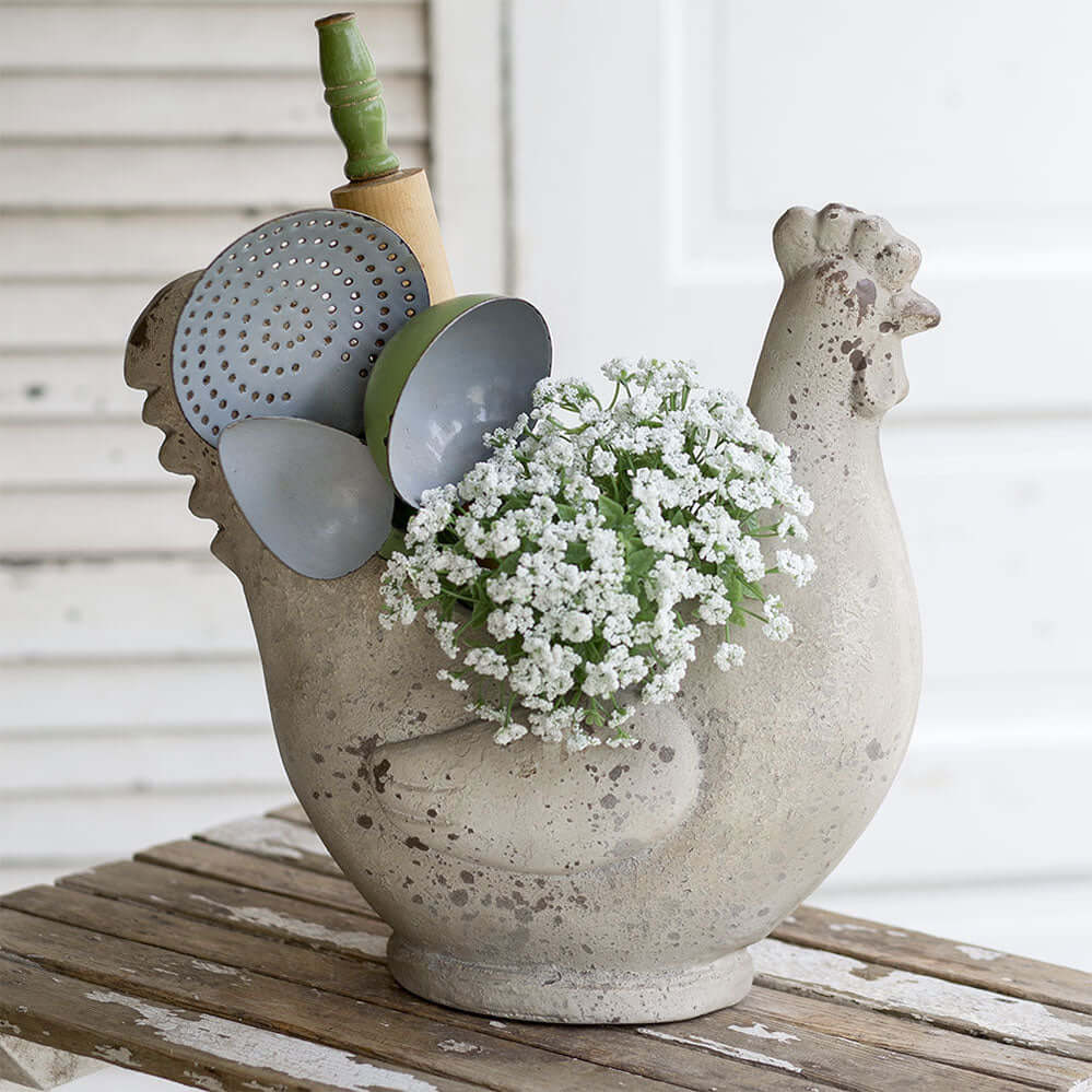 Rustic farmhouse chicken container holding flowers and kitchen utensils, adding country charm to decor.