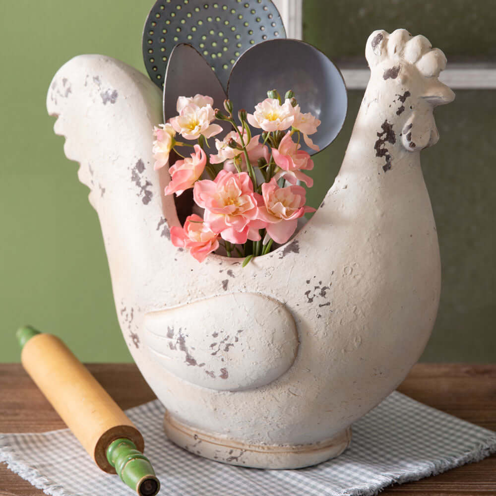 Rustic farmhouse chicken container holding flowers and utensils, perfect for country-themed home decor.