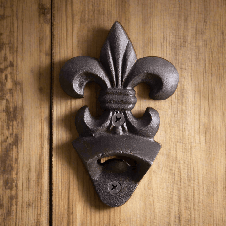 Vintage-style cast iron Fleur-de-Lis wall-mounted bottle opener on wooden surface.