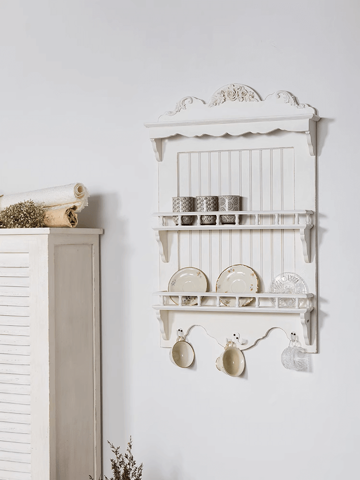 French country wall-mounted dish rack in white, showcasing plates and cups, adding rustic elegance to a kitchen.