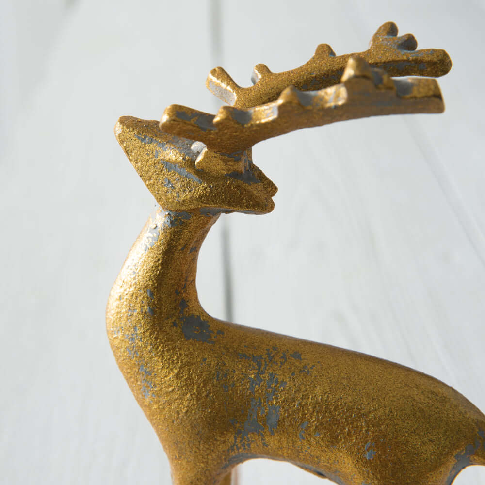 Gold reindeer figurine showcasing intricate details and elegant silhouette on a light wooden surface.