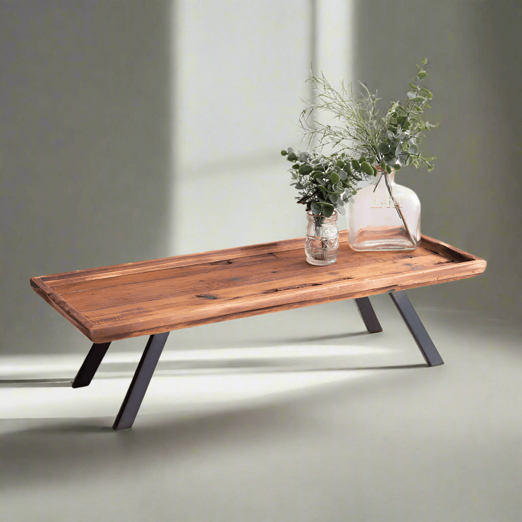 Industrial serving tray with natural wood surface and black metal legs, styled with a vase and greenery.