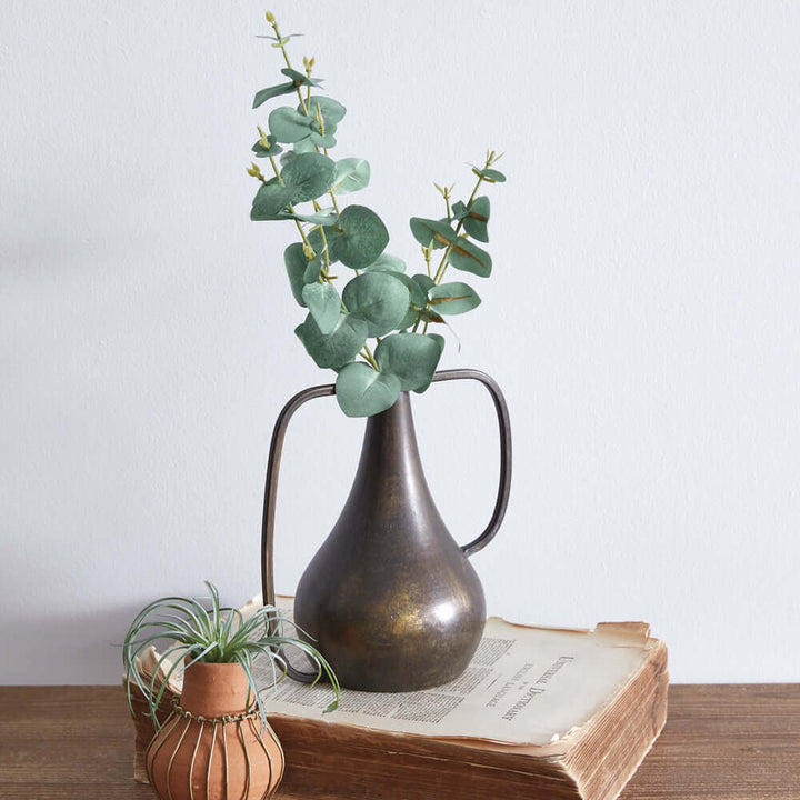 Antique Bronze Boho Vase with eucalyptus leaves, showcasing rustic charm and vintage style on a wooden table.