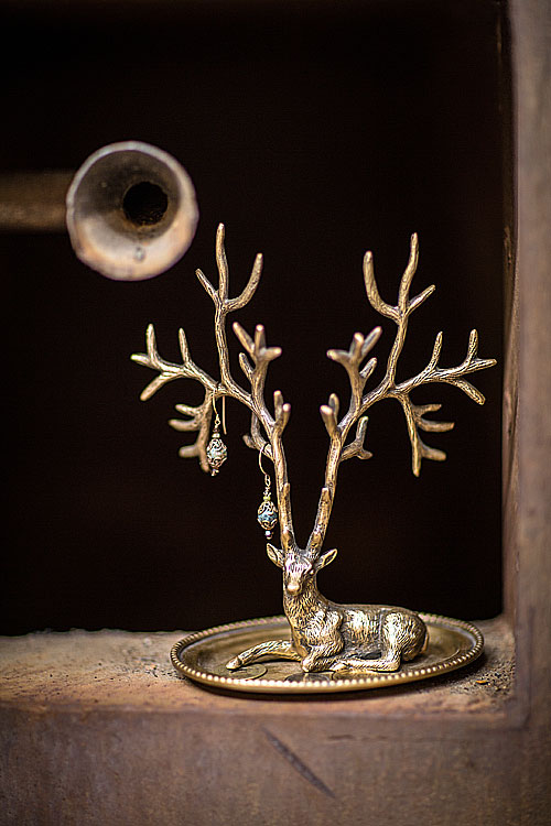 Antique brass deer jewelry holder with branch-like antlers, elegantly showcasing intricate details on a vanity.