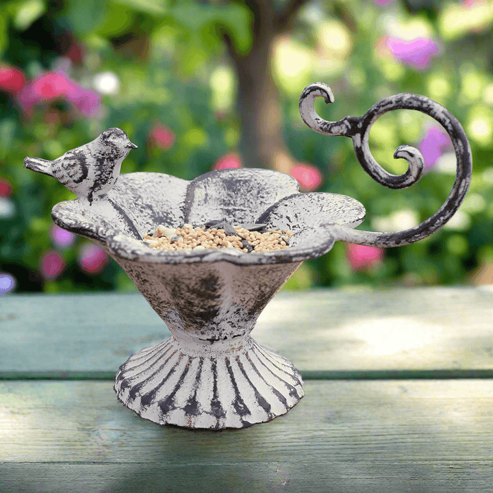 Rustic cast iron bird feeder with flower basin and bird figurine, ideal for outdoor decor and garden charm.