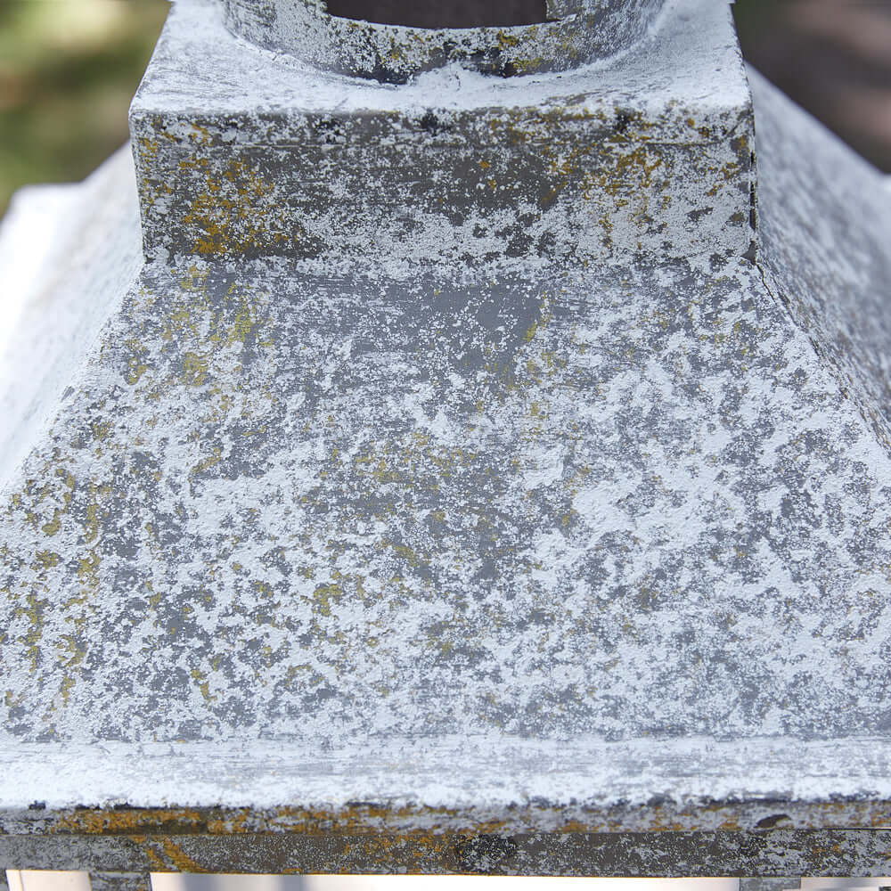 Close-up of a rustic farmhouse lantern with a distressed weathered metal finish.