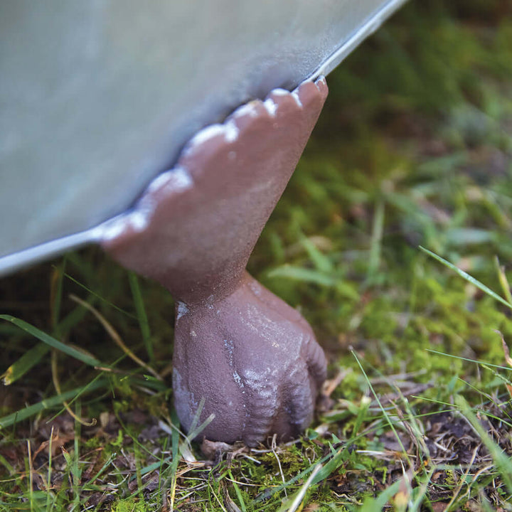 Close-up of a rustic metal clawfoot planter leg on grass, showcasing its charming design and durable construction.