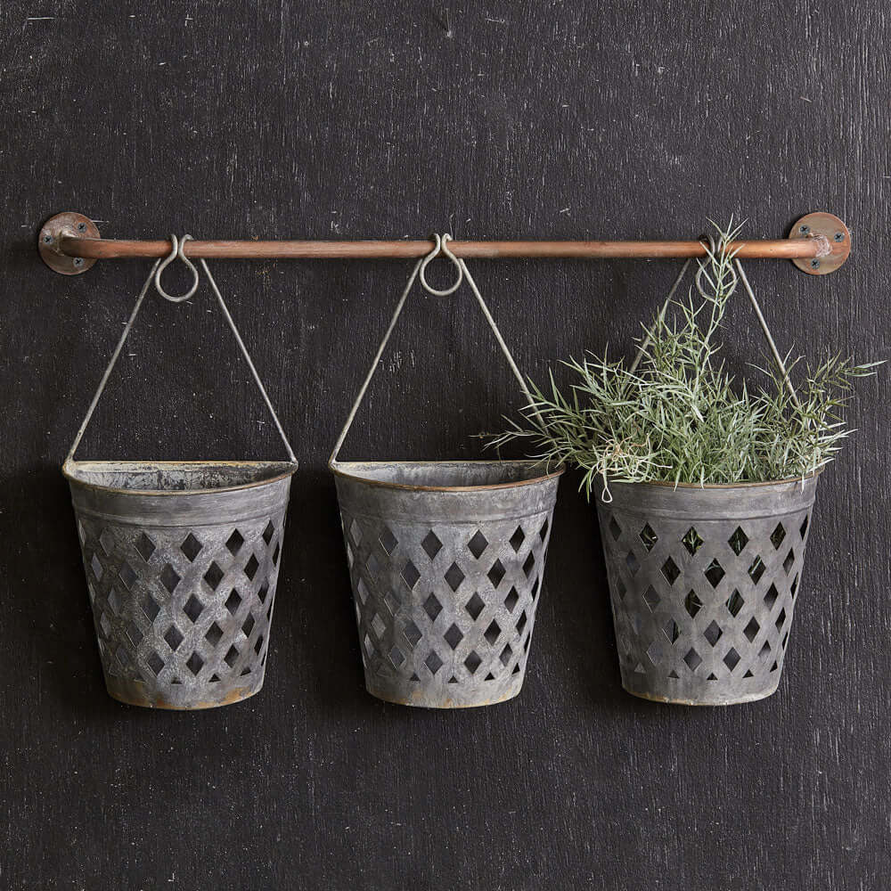 Rustic hanging lattice basket planters on a wall, showcasing greenery in vintage metal containers.