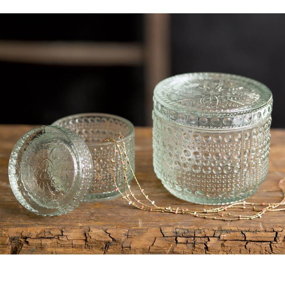 Antique inspired decorative cut glass containers set on rustic wooden surface, showcasing intricate vintage patterns.