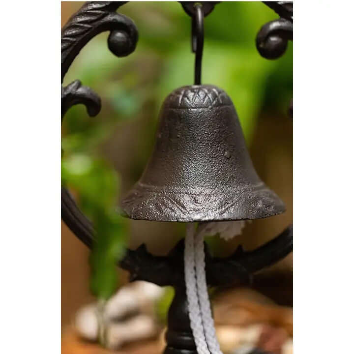 Close-up of a rustic cast iron rooster dinner bell with ornate frame and hanging rope, perfect for farmhouse decor.