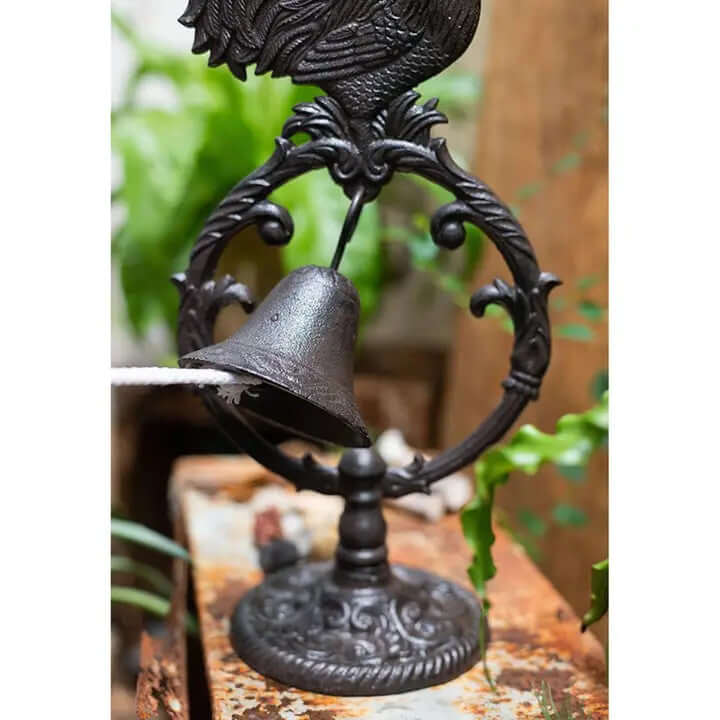 Cast iron rooster dinner bell with ornate frame, perfect for rustic farmhouse decor and functional use in entryways or gardens.