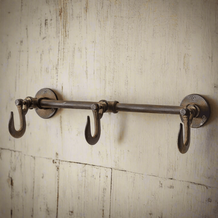 Industrial three hook wall rack made of durable cast iron with a rustic finish, perfect for organizing and decorating spaces.